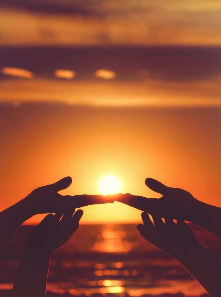 a silhouette of hands touching Infront of a sunset creating new bonds in family therapy