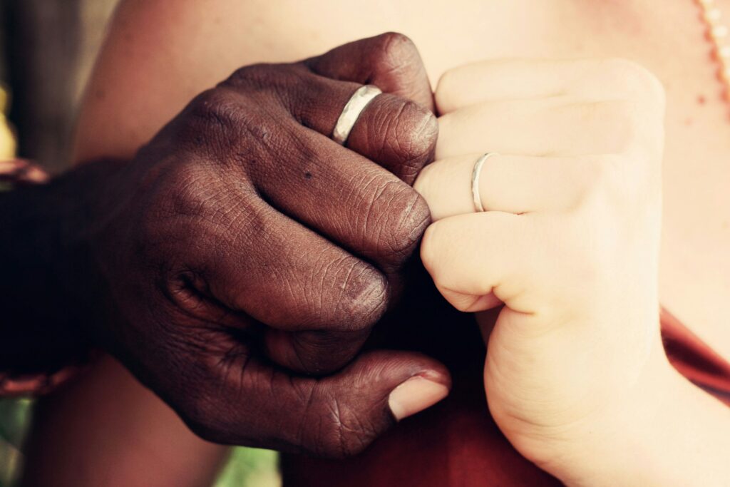 two hands touching with wedding bands on for unity during marriage counseling