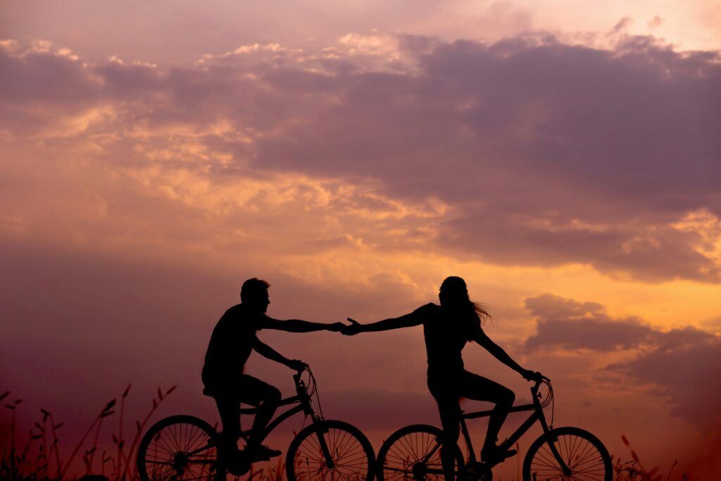 a silhouette of a couple riding bicycles outside at sunset