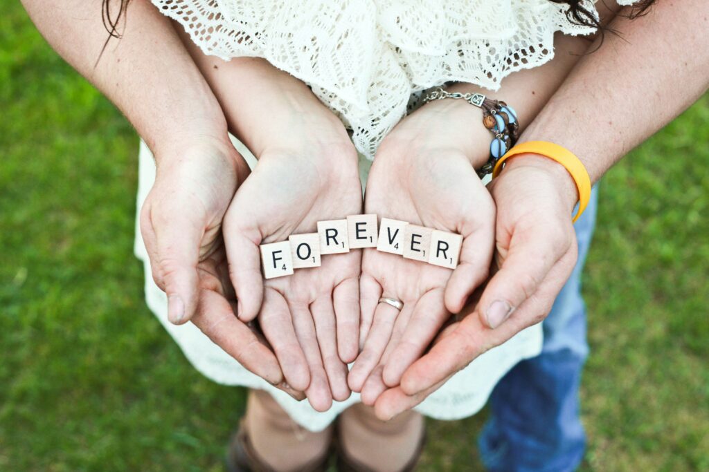 hands together holding scrabble tiles spelling the word "forever" feeling the results of family therapy