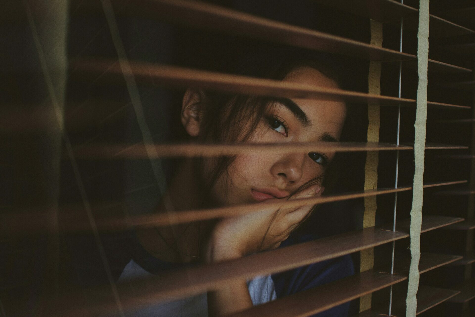 a girl staring out the window looking melancholy showing a need for individual counseling