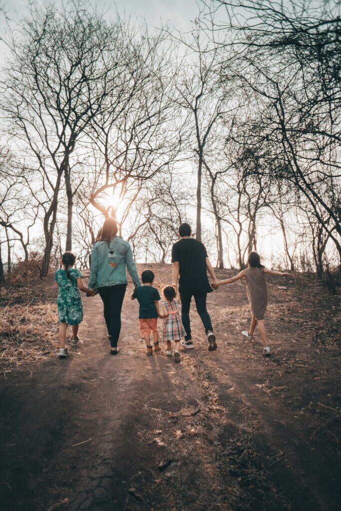 A family holding hands walking in the woods having completed therapy for familes