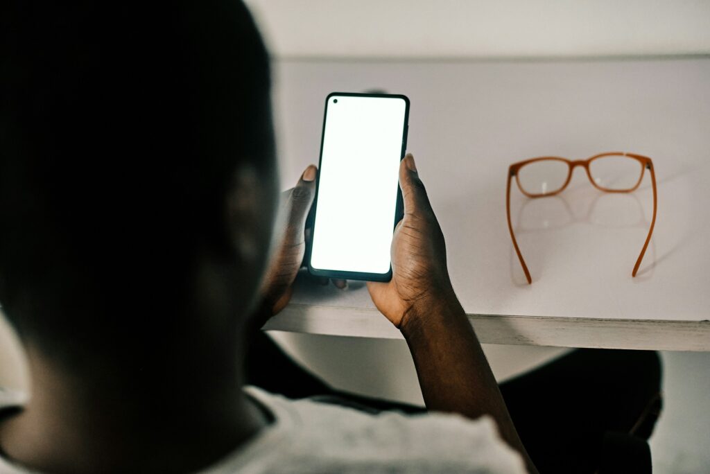 a guy, from behind, holding the phone up to look at it for a phone therapy session