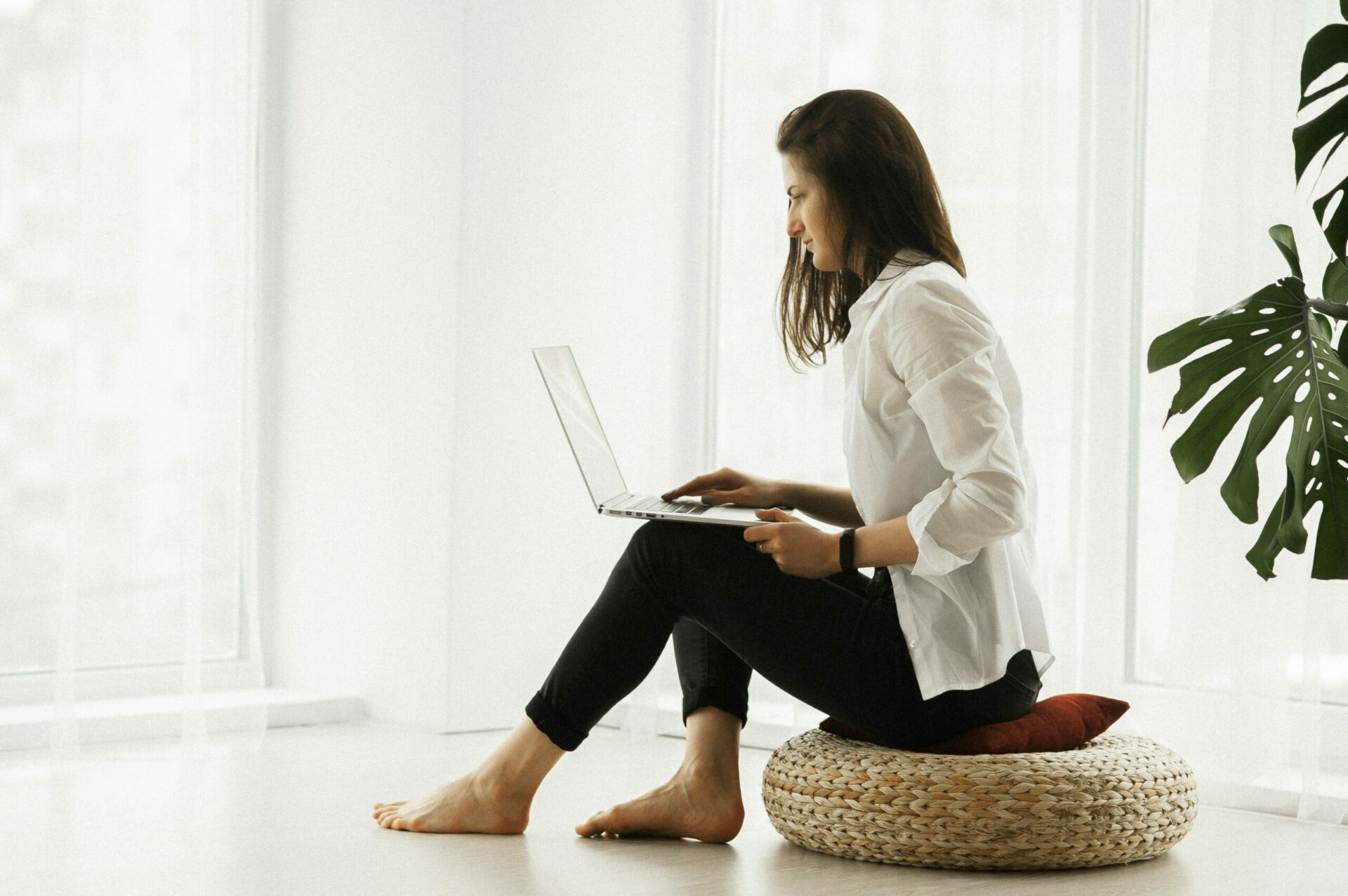 lady sitting on a stool with a laptop in a comfortable space having a teletherapy session