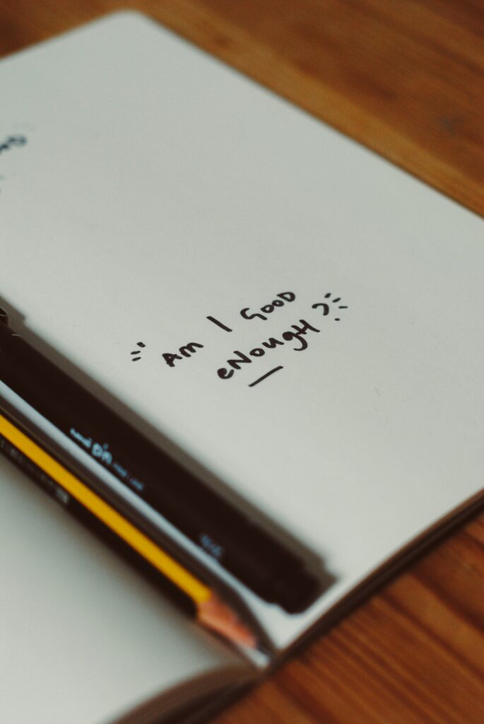 a notebook with the words "Am I Good Enough" in it showing the need for individual therapy