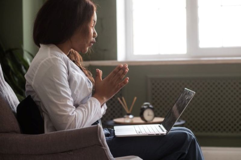 Online Christian counselor praying with a client during a virtual therapy session, promoting faith-based mental health support.